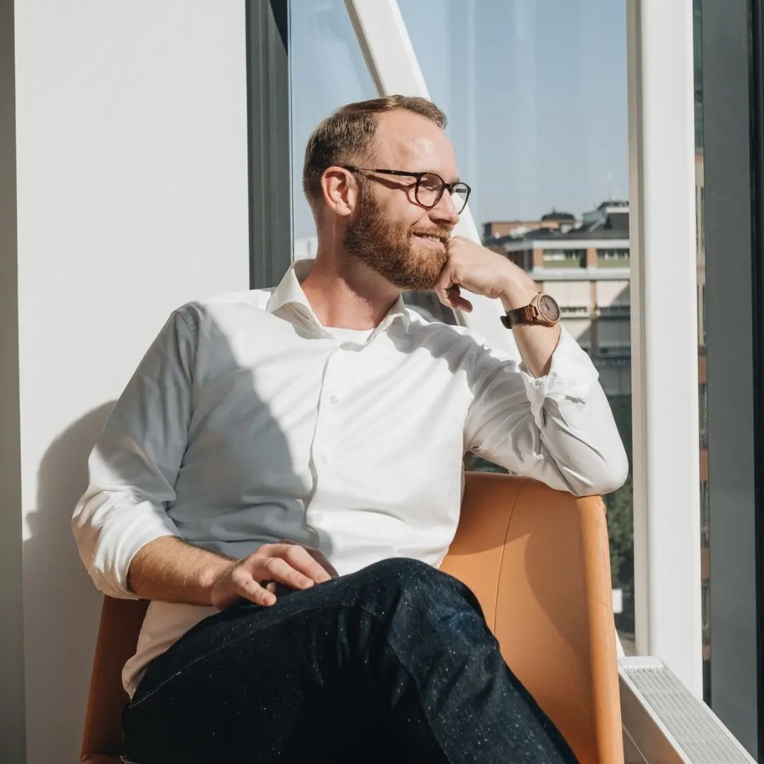Andréas Jonsson sitter i en fotölj och tittar ut ur ett stort fönsterparti.