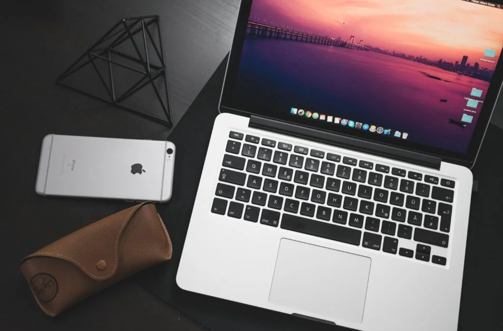 Laptop, mobiltelefon och glasögonfodral på svart skrivbord