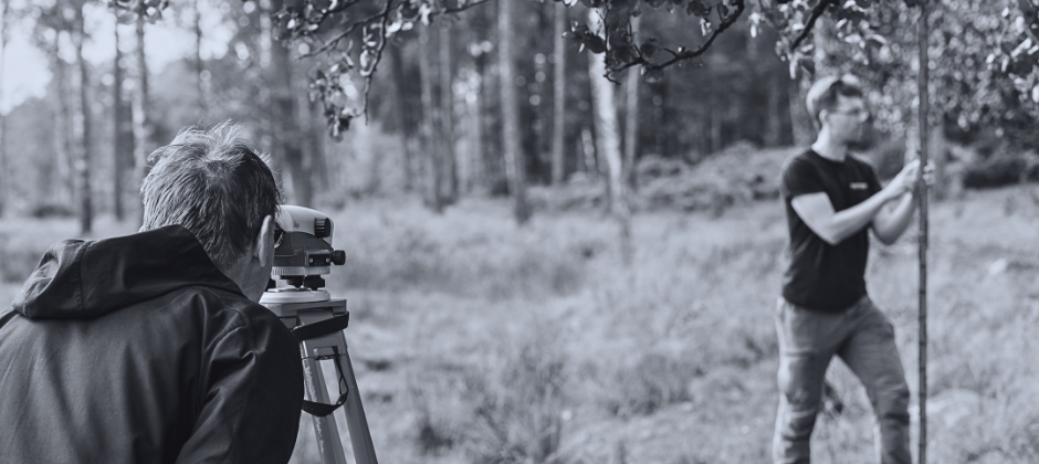 Två mätningsingenjörer arbetar i utomhusmiljö.