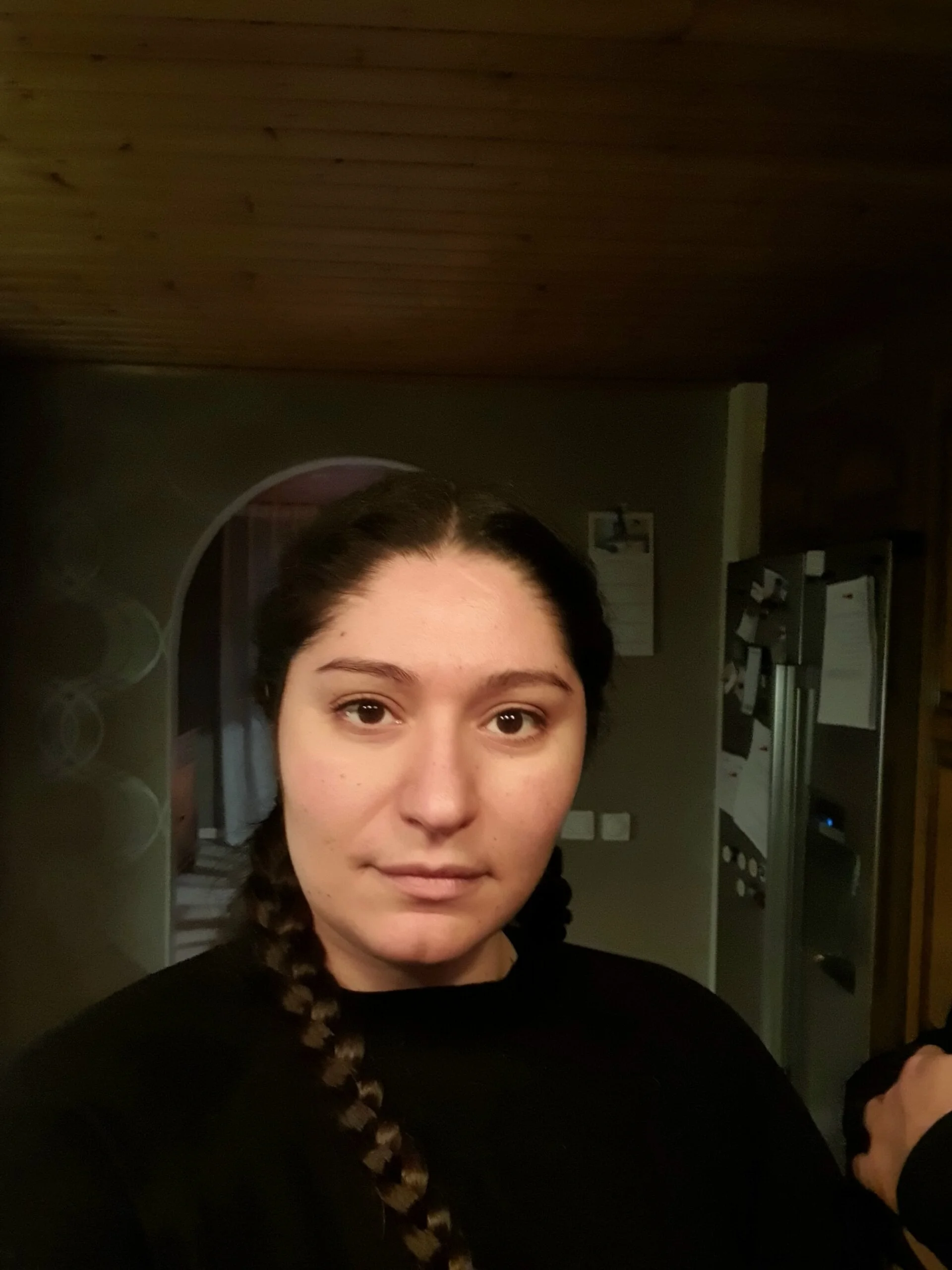 Halvkroppsbild på Sheida Boustman, studerande på Teknikhögskolan som tar en selfie i ett mörkt rum med kroppen och blicken riktad rakt mot kameran..