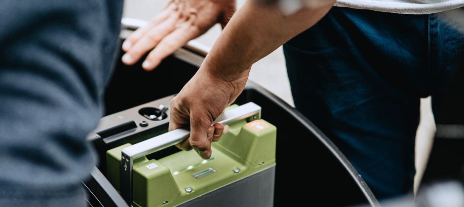 Batteritekniker lyfter upp ett batteri ur ett fordon.