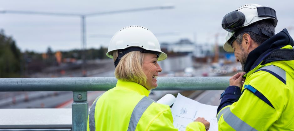 Byggprojektledare diskuterar ritning på byggarbetsplats.