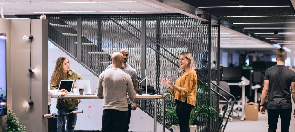 Projektutvecklare står samlade runt ett bord i kontorsmiljö.