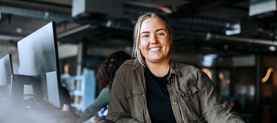 Pythonutvecklare inom AI tittar in i kameran i kontorsmiljö.