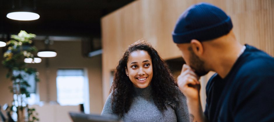 Tekniska säljare står vända mot varandra och skrattar i kontorsmiljö.