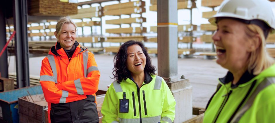 Transportledare i varselställ skrattar och konverserar med varandra i utomhusmiljö.