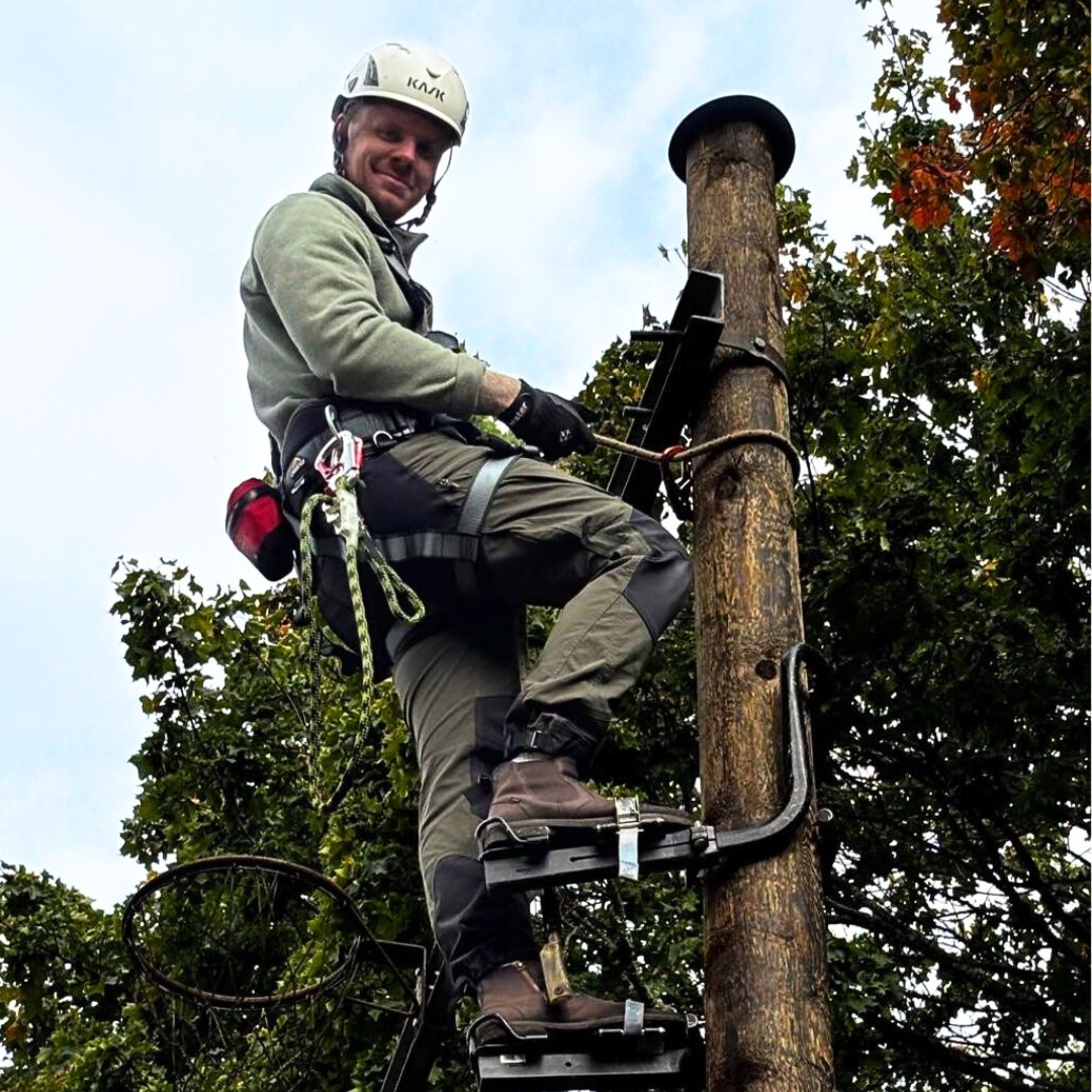 Alexander Blomkvist klättrar i elstolpe och ler mot kameran.