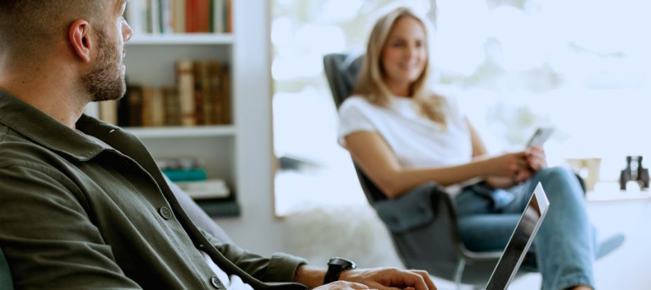 Man och kvinna sitter i varsin fotölj i ljus miljö.