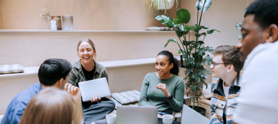 Studerande sitter samlade runt ett bord och skrattar.