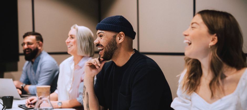 Studerande sitter samlade runt bord och skrattar.