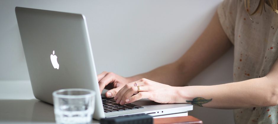 Inzoomad bild på händer framför en bärbar dator.