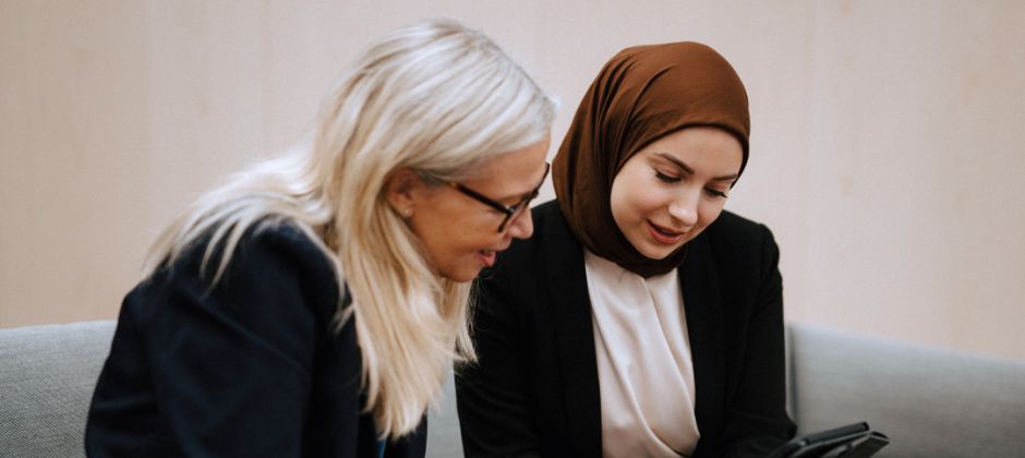 Utbildare och studerande sitter i soffa och tittar på en surfplatta.