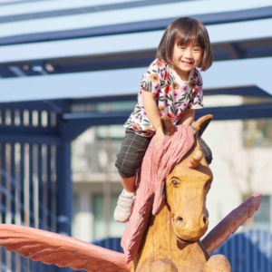 Liten flicka klättrar på en leksaksenhörning i Täby Park.